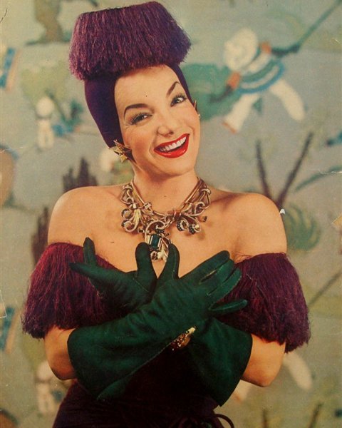 Carmen Miranda in costume with towering hat and long gloves